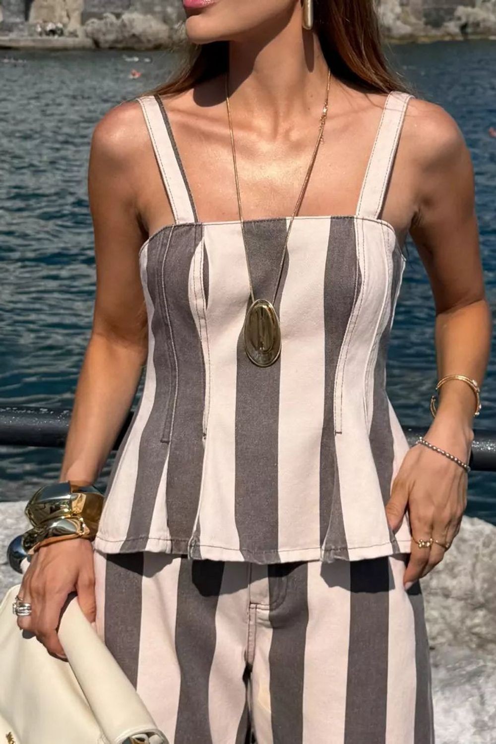 Blusa Alcance Dolce Vita listrada em rosa e cinza, detalhe do busto com costuras e colar dourado Imagem principal do produto