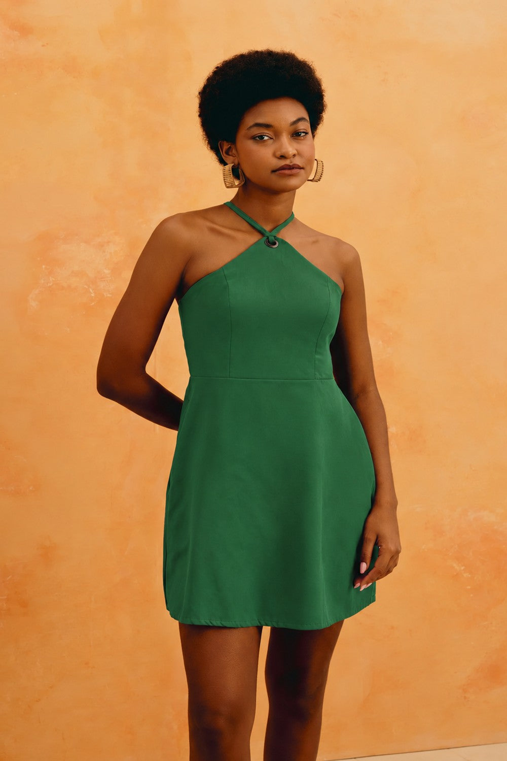 Vestido curto Cacay verde com detalhe de ilhós no decote halter, vestido na modelo de frente Imagem principal do produto